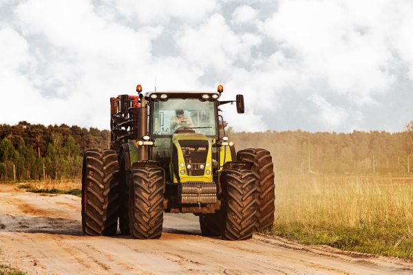 Big tractor on a road at countryside near meadows