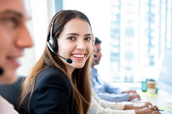 Smiling beautiful friendly woman working in call center office with team as the customer care operators